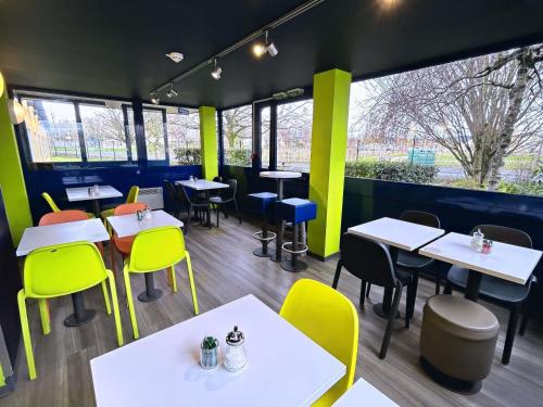 a restaurant with white tables and yellow chairs at ibis Budget Beaune in Beaune