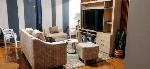 a living room with a couch and a tv at Morada Living Bello HomeStay in Bello