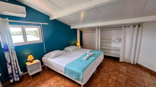 a bedroom with a bed and a blue wall at Les 2 Cocotiers - Maison d'hôtes d'Eugénie in Sainte-Luce