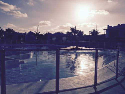 basen ze słońcem w tle w obiekcie Sun Beach Apartamento nº 26 w mieście Caleta De Fuste