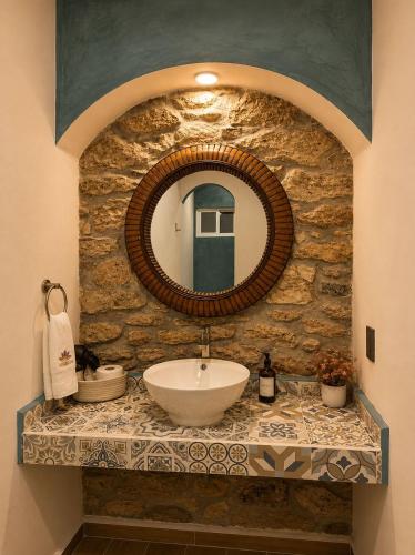 a bathroom with a sink and a mirror on a stone wall at Hotel Bugambilia in Zimapán