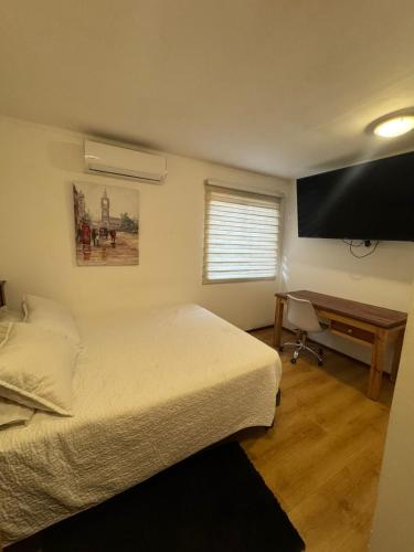 a bedroom with a bed and a desk and a television at Hostal Almendral in San Felipe