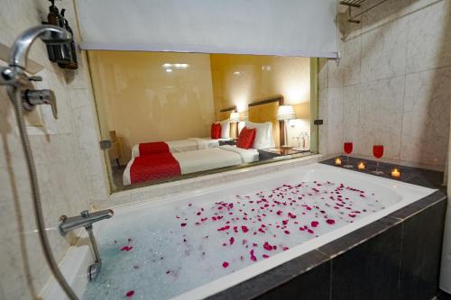 a bathroom with a tub filled with red rose petals at Hotel Amber Palace in Gurgaon