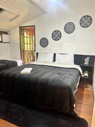 a bedroom with a large bed with a black blanket at Hari Eco Pousada in Brumadinho