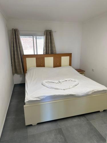 a bedroom with a bed with white sheets and a window at carmel cabins suite nu 9 in Yājur