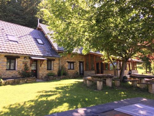 a brick house with picnic tables and a tree at La Bernadole - Chambres d'Hôtes in Aleu