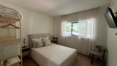 a bedroom with a white bed and a window at Refúgio do Tâmega in Penafiel
