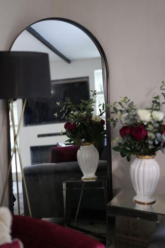 a mirror with two vases with flowers on a table at Pasture Side House in Clayton