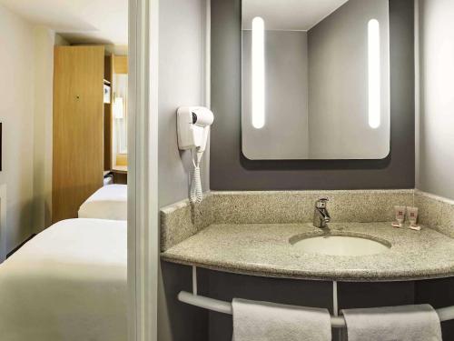 a bathroom with a sink and a mirror and a bed at ibis Copacabana Posto 5 in Rio de Janeiro