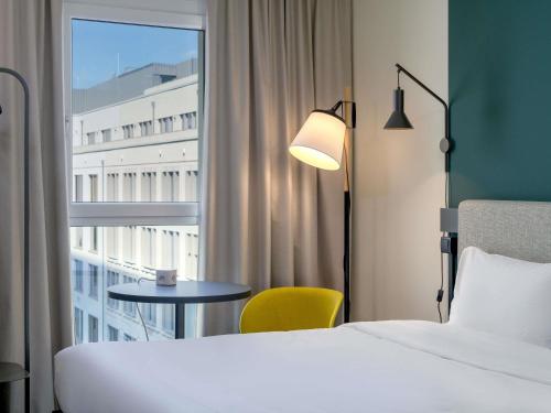 a hotel room with a bed and a table and a window at ibis Leipzig City in Leipzig