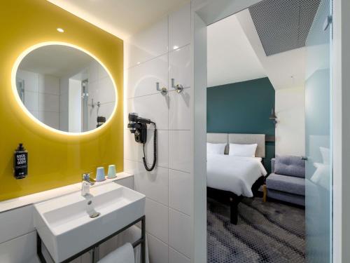 a bathroom with a sink and a mirror and a bed at ibis Leipzig City in Leipzig