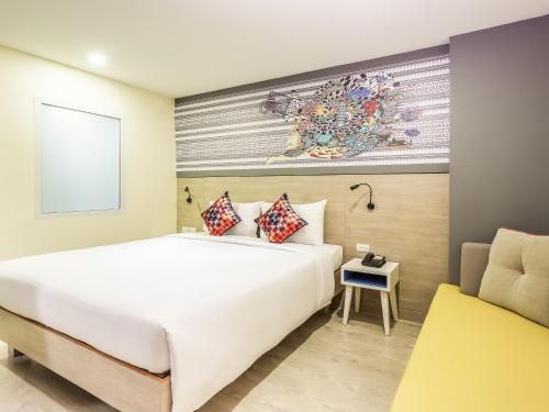 a bedroom with a large white bed and a chair at Ibis Styles Bangkok Sukhumvit 50 in Bangkok