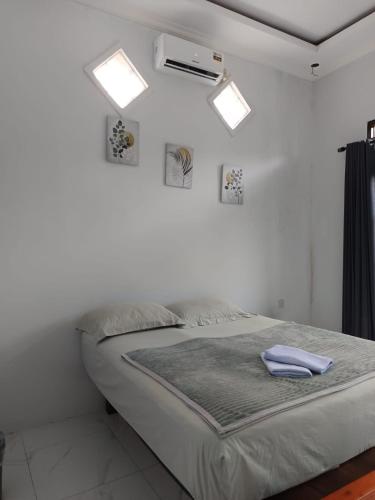 a bed in a white room with two lights at Raja Ampat Sandy Guest House in Saonek