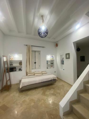 a bedroom with a bed in a white room at Menzel à Midoun in Al Maqārisah