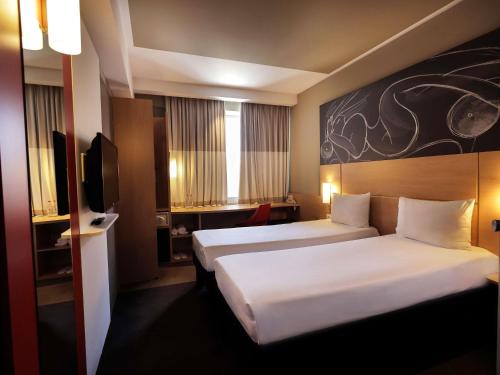 a hotel room with two beds and a television at ibis Yerevan Center in Yerevan