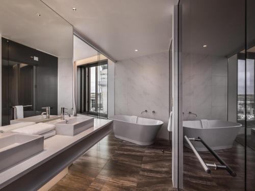 a bathroom with two sinks and two mirrors at Novotel Christchurch Airport in Christchurch
