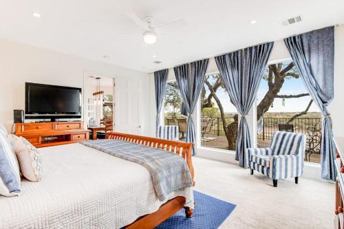 a bedroom with a bed and two chairs and a television at Natural Cliffside Oasis with Impressive Views, Gas Fireplace and Dock in Spicewood