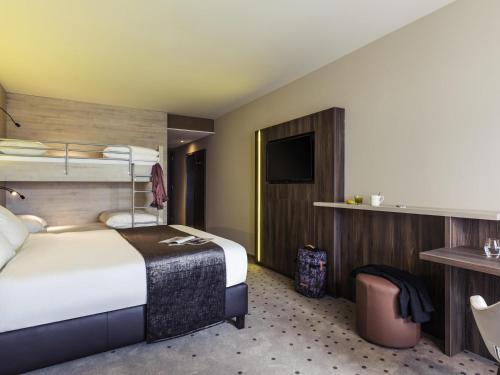 a hotel room with a bed and a tv at Mercure Blankenberge in Blankenberge