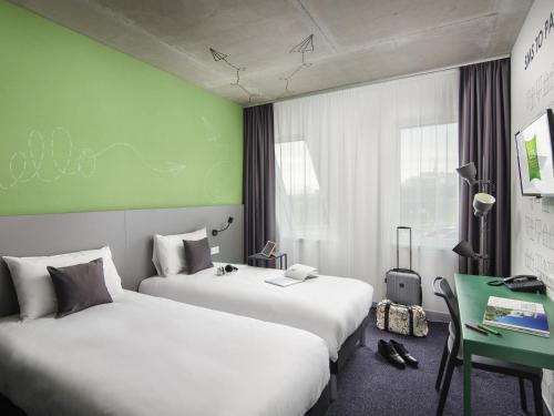 a hotel room with two beds and a green wall at ibis Styles Budapest Airport in Vecsés