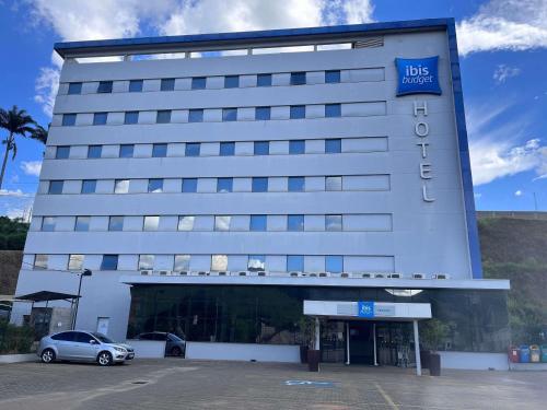 a hotel with a car parked in a parking lot at ibis budget Manhuaçu in Manhuaçu