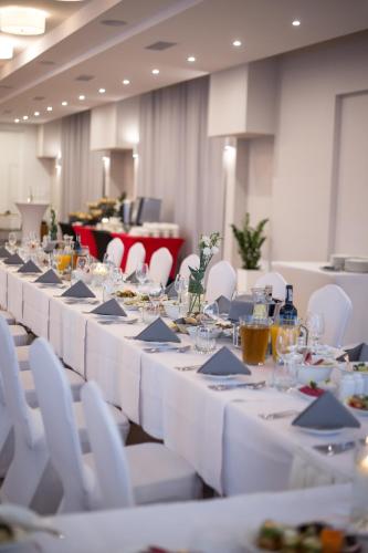 a long table with white tables and white chairs at Hotel Mazovia Airport Modlin in Nowy Dwór Mazowiecki