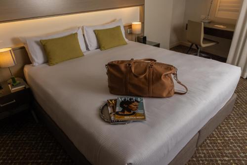 a bag and a book sitting on top of a bed at Point Hotel in Brisbane
