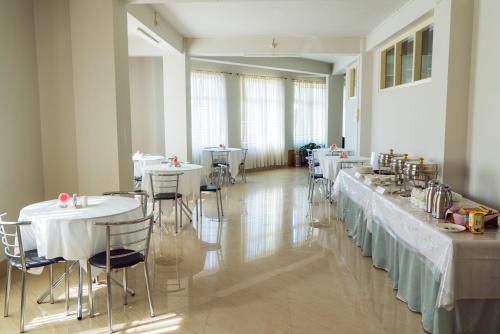 a dining room with tables and chairs with white tables at Hotel Ariel in Kohīma