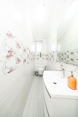 a white bathroom with pink flowers on the wall at Ilma Apartment in Trogir