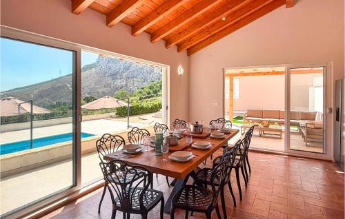 a dining room with a table and chairs and a large window at Gorgeous Home In Solin in Solin