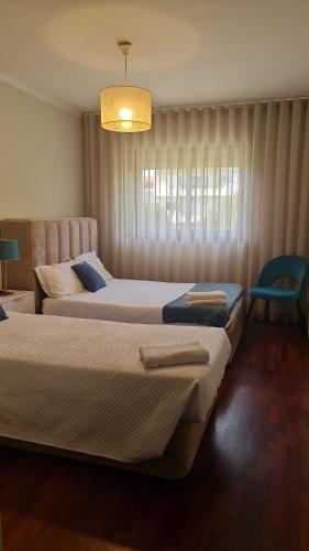 a bedroom with two beds and a chandelier at Barra's Beach Apartment in Praia da Barra
