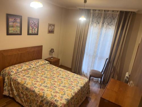 a bedroom with a bed and a table and a window at Piso Salón Paraíso in Bueu