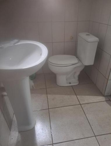 a bathroom with a white toilet and a sink at Pousada Praia Grande in Mongaguá