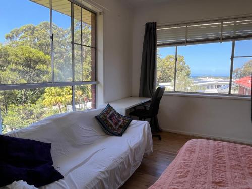 a bedroom with a bed and a desk and windows at 1 Bedroom Flat with Private Kitchen & Ensuite in Bulli