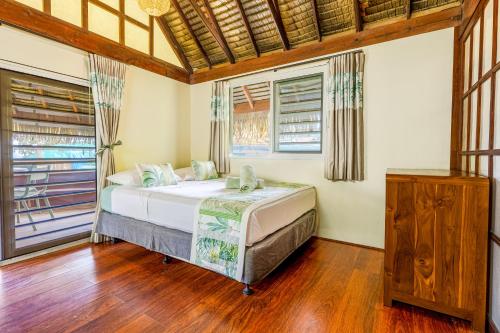 a bedroom with a bed in a room with windows at Fare Aute Beach in Vaianae