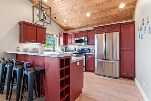 a kitchen with red cabinets and a kitchen island with bar stools at Upper Deck by Simple Life Rentals in Sturgeon Bay