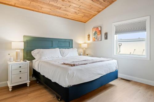 a bedroom with a blue bed and a window at Upper Deck by Simple Life Rentals in Sturgeon Bay