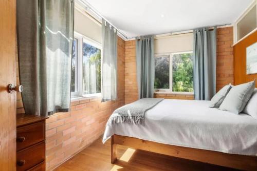 a bedroom with a bed and two windows at Saltwinds - Steps to Beach & Lighthouse in Aireys Inlet