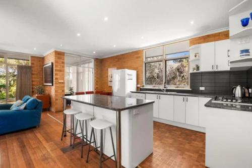 a kitchen with white cabinets and a blue couch at Saltwinds - Steps to Beach & Lighthouse in Aireys Inlet
