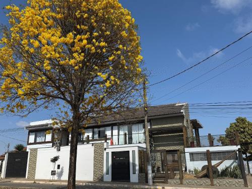 a yellow tree in front of a white house at Pousada Carro de Boi in Lavras