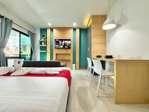 a bedroom with a bed and a table and a kitchen at Chalong - Studio Service Apartment - Phoomjai in Ban Klang