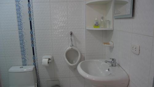a bathroom with a sink and a toilet and a urinal at Casa jardín Roqui in Puno