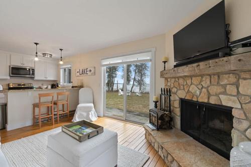 a living room with a stone fireplace with a flat screen tv at Tranquility Bay Getaway by Simple Life Rentals in Sister Bay