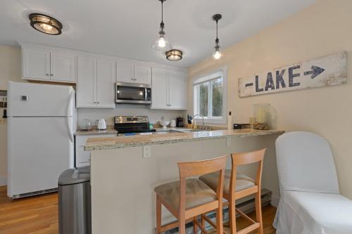 a kitchen with white cabinets and a counter with two chairs at Tranquility Bay Getaway by Simple Life Rentals in Sister Bay