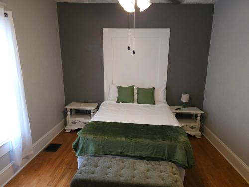 a bedroom with a large bed with green sheets and two tables at Huge 4-Bedroom Historic Home & Game Room in Goldsboro