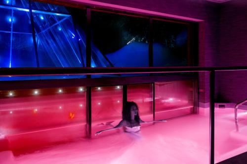a young girl is in a pool with pink lights at Val di Luce SPA Resort in Abetone