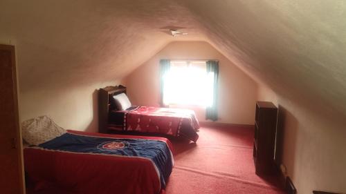 a attic room with two beds and a window at The Sparkle House in Cedar Rapids
