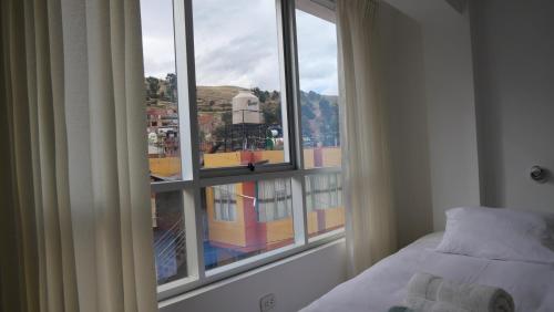 a bedroom with a window with a view of a city at Casa jardín Roqui in Puno