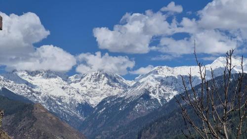 a snow covered mountain range with clouds in the sky at Ivory Nest Villa in Chamba