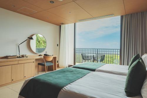 a bedroom with a bed and a large window at Sankara Hotel & Spa Yakushima in Yakushima
