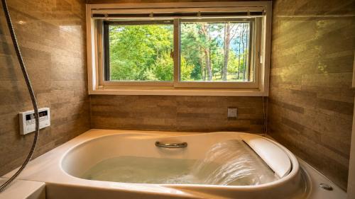 a bath tub with a window in a bathroom at アルプスシャレー in Hokuto